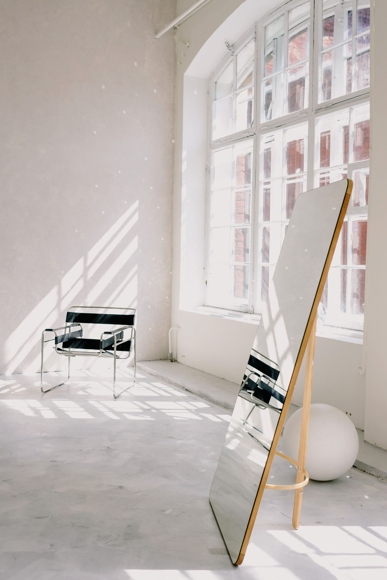 Espaço minimalista com pavimento mineral claro, espelho e luz natural